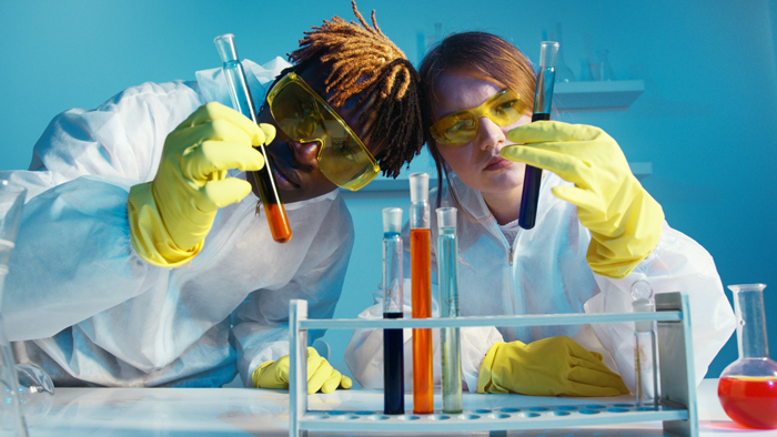 image of two young researchers holding up and studying test tubes